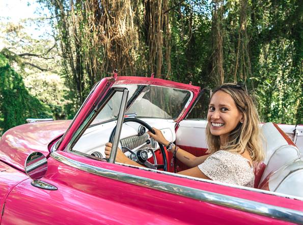 6 Cool things to do in Cuba A tourist pretending to drive a classic American car in Cuba