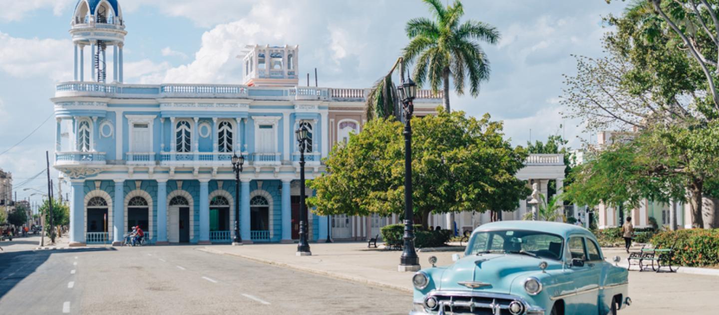 Um carro clássico azul estacionado ao lado do Parque José Martí em Cienfuegos, Cuba