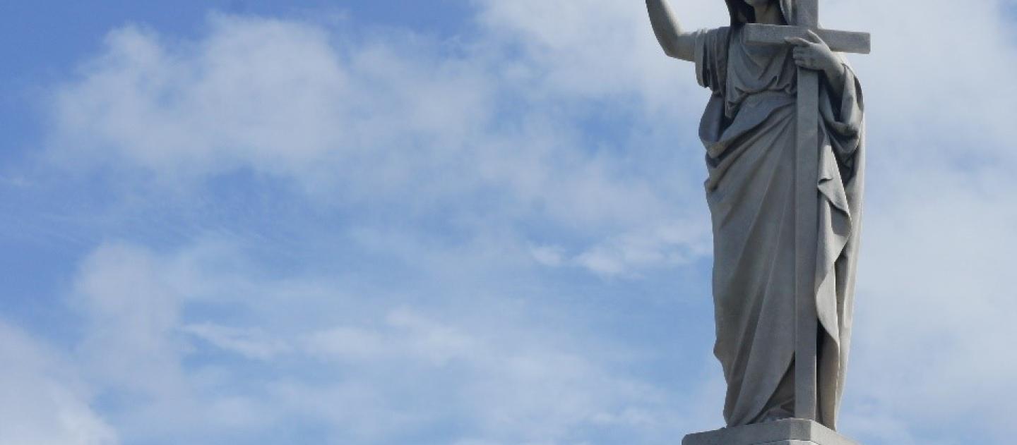 a bird perches on the hand of a marble monument