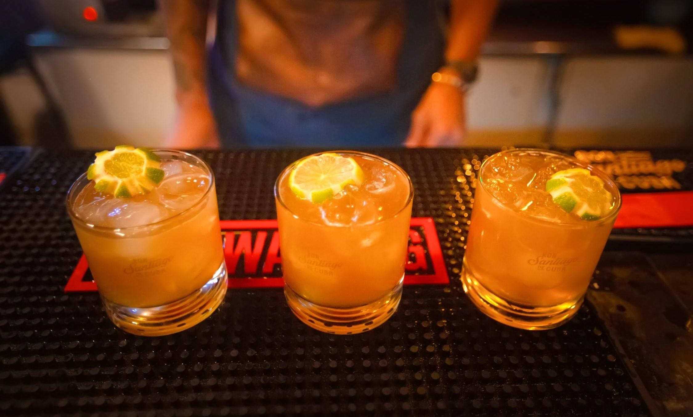 Close up of three lime garnished cocktails on a bar mat