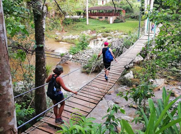 Escape the Grind in Topes de Collantes Trekkers cross a bridge in Topes de Collantes