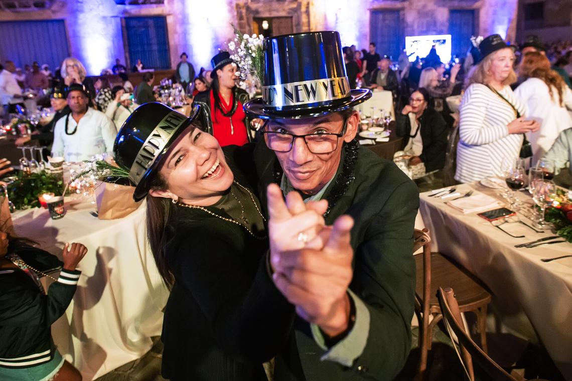 A happy couple dances while wearing black hats with Happy New Years on the band