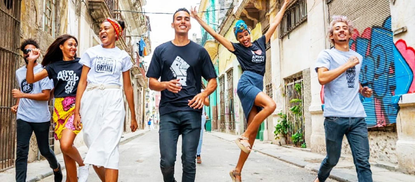 A cheerful group of hip 20-somethings walk down the street wearing designer Afro-Cuban themed t-shirts